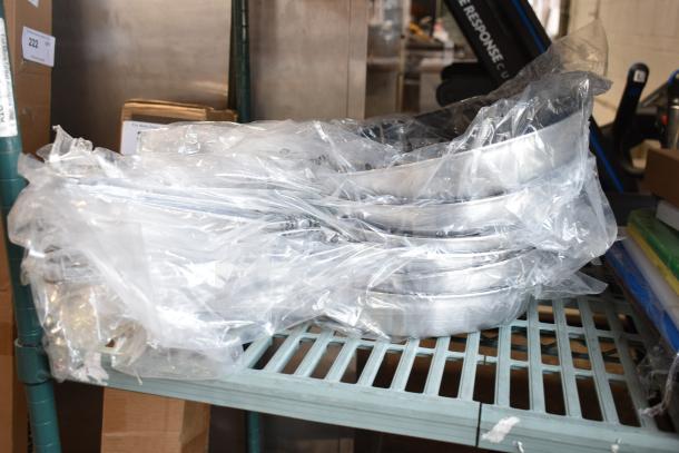 Six brand new 12" Choice Aluminum Non-Stick Fry Pans in plastic wrap, light scratch and dent condition, on a shelf.