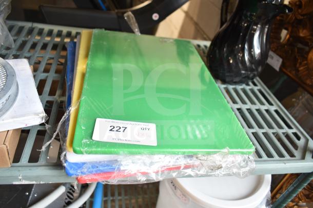 Stack of new cutting boards in plastic wrap, including green, yellow, white, blue, and red. Auction lot 227 tag visible.