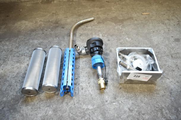 Five new scratch and dent items including metal cylinders, a blue grip tool, and accessories in a box labeled "228."