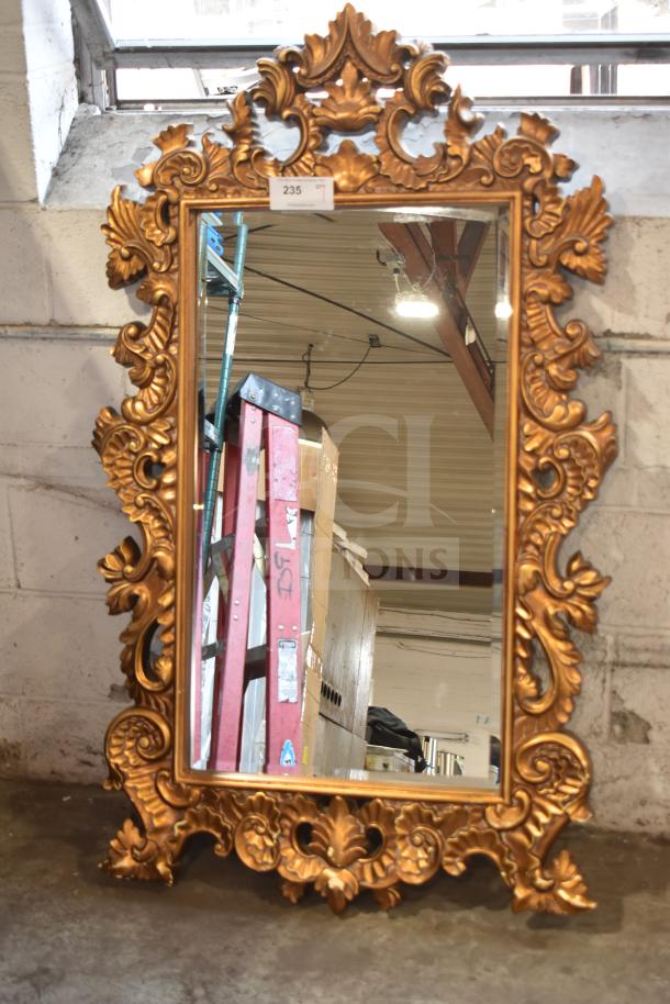 Ornate gold-framed mirror with intricate floral carvings, rectangular shape, excellent condition. Tag displaying "235" on top.