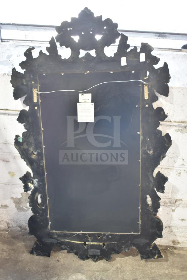 Ornate vintage mirror with intricate black frame, back view showing hanging wire and attached label indicating item number 2199-B.