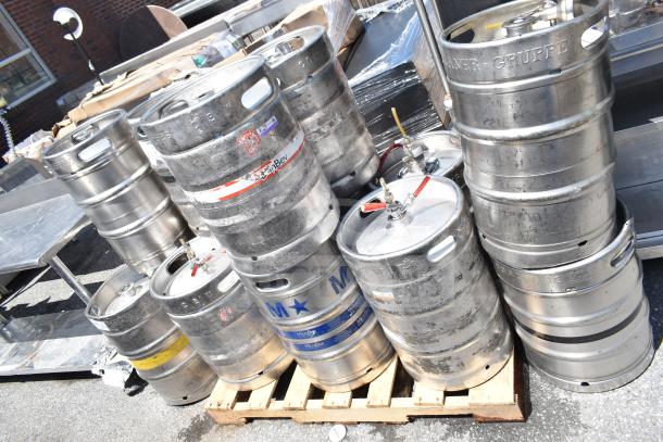 10 used metal kegs, including half-size barrel kegs, stacked on a pallet. Various labels and brands visible.