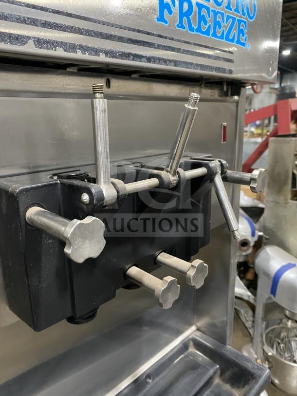 Electro Freeze stainless steel soft serve machine, twin/twist, 2 hoppers, 3 dispensers, on casters, shown in good condition.