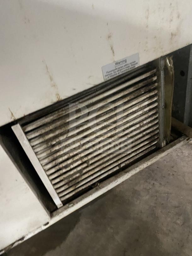 Stainless steel ice cream cabinet with slanted glass, rear lift-open access, visible vent, some wear marks.