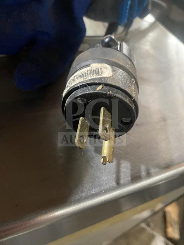 Commercial-grade power plug for stainless steel ice cream/frozen yogurt dipping cabinet, seen in close-up. Labels indicate specifications.