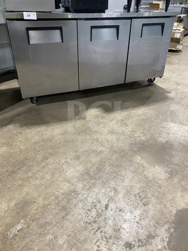 True TUC-72 3-door stainless steel undercounter refrigerator on casters, features poly coated wired racks, serial 6718114.