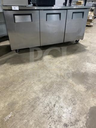 True TUC-72 3-door stainless steel undercounter refrigerator on casters, features poly coated wired racks, serial 6718114.