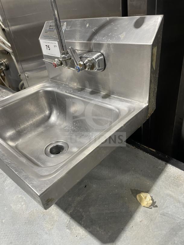 Jimex stainless steel wall-mount hand sink with back splash, dual faucet, and minor wear. Auction tag "75 QTY" visible.