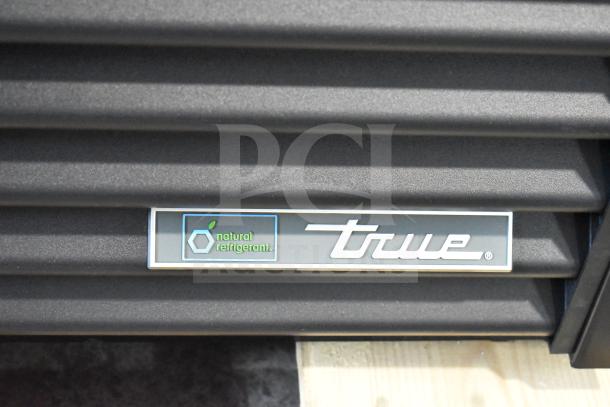 True GDM-33-HC-LD cooler logo with "natural refrigerant" label, showing brand detail on black louvered panel.