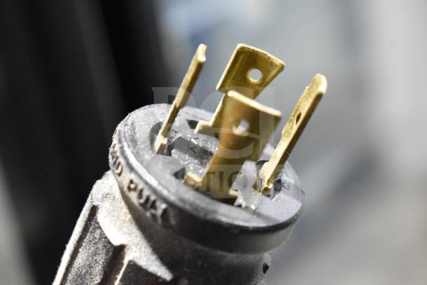 Close-up of a power plug for a 2019 True GDM-72F-HC commercial freezer. Features brass prongs and a black plastic housing.