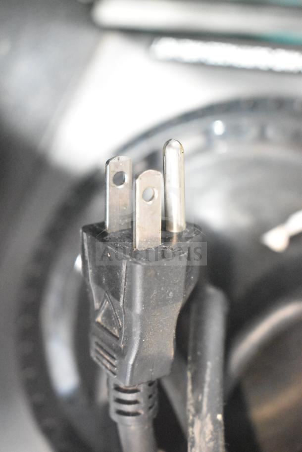 Close-up of a three-prong plug attached to a Bunn 33200.0015 VPR coffee brewer, highlighting electrical compatibility.
