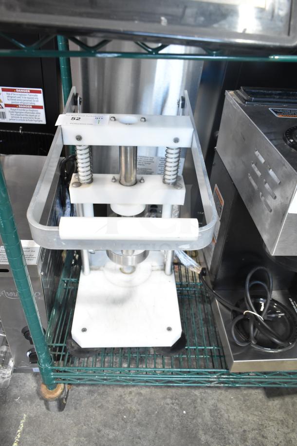 Heavy-duty countertop pineapple corer with metal springs and base, used condition, on steel wire shelf.