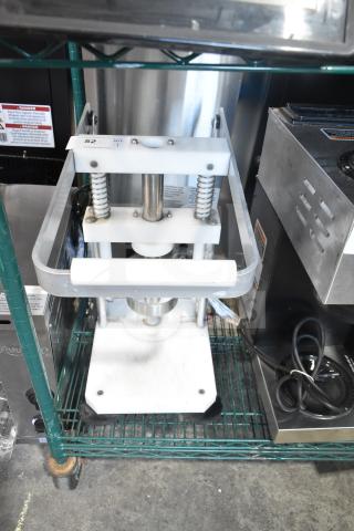 Heavy-duty countertop pineapple corer with metal springs and base, used condition, on steel wire shelf.