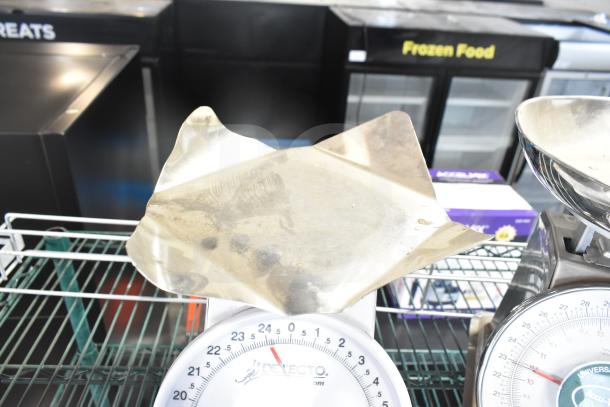 Detecto T25BN scale and Accu-Weigh Yamato SM(N) scale on white rack. Visible dials and stainless steel weighing platforms.