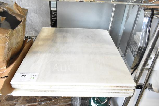 Five brand new white cutting boards with minor scratches, stacked on a shelf. Auction label "67 Qty x5" visible.