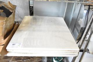 Five brand new white cutting boards with minor scratches, stacked on a shelf. Auction label "67 Qty x5" visible.