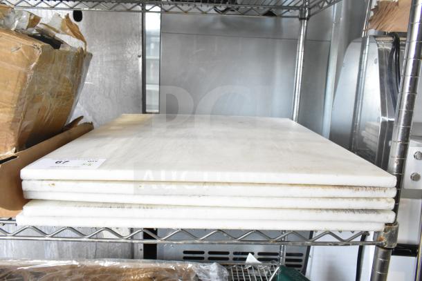 Five white cutting boards, brand new, with minor scratches, stacked on a metal shelf. Tag reads "5 Times Your Bid."