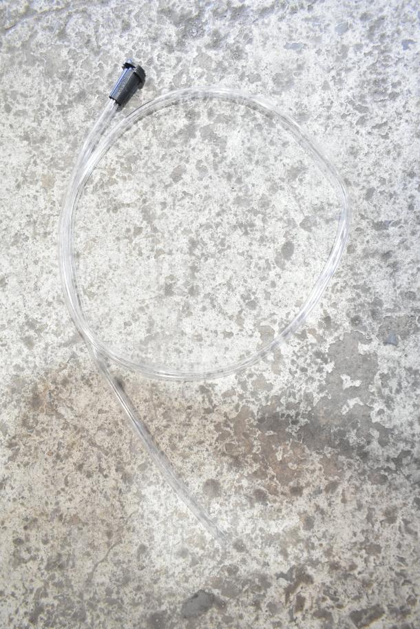 Alt text: Clear hose with connector for Simpson 4,500 PSI pressure washer spray gun, displayed on concrete surface.