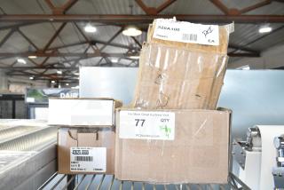 Four boxes, labeled and partially open, on a metal shelf. Items include thermocouple, control board, and pilot assembly. New with minor dents.