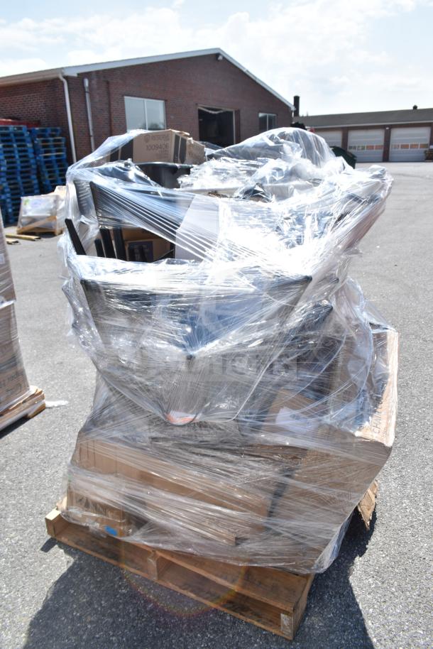 Plastic-wrapped pallet of scratch and dent items, including a work table and glasses, on an outdoor lot. Multiple boxes visible.