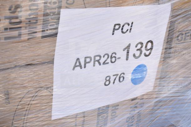 Clear wrapped pallet with items labeled "APR26-139" and "PCI." Contains assorted household items like trash bags and towels.