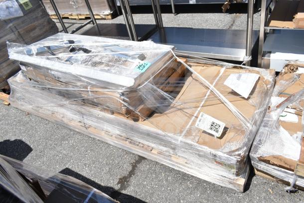 Seven new scratch and dent items on a pallet, including a pan rack and wire shelves, wrapped in plastic.
