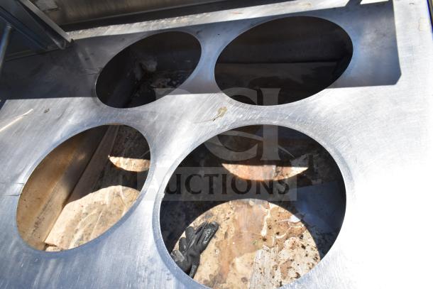 Commercial prep table with four round cut outs, two drawers for sauce pots, on commercial casters. Visible wear.