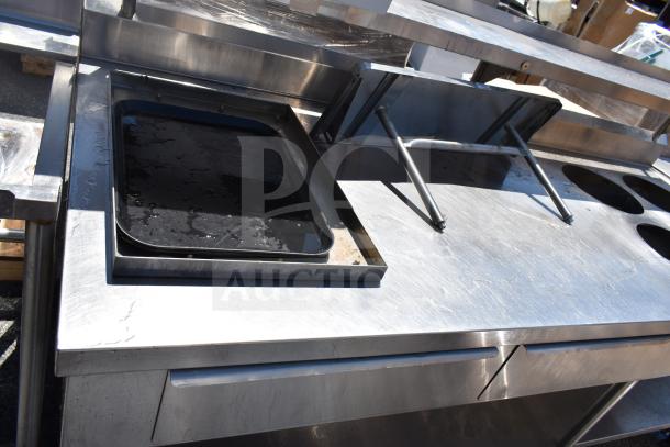 Commercial prep table with four round cutouts, two drawers, and sauce pot cutouts on commercial casters, stainless steel.