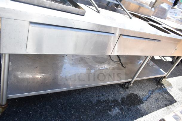 Commercial stainless steel prep table with four round cutouts, two drawers, sauce pot cutouts, on sturdy casters.