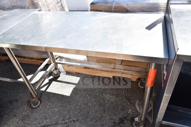 Commercial stainless steel table on wheels, sturdy condition, features visible Win-Holt label, suitable for heavy-duty use.