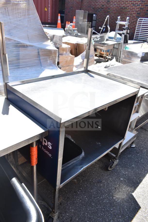 Commercial portable counter with under shelf, on commercial casters, in used condition. Sturdy metal construction.