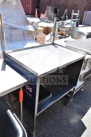 Commercial portable counter with under shelf, on commercial casters, in used condition. Sturdy metal construction.