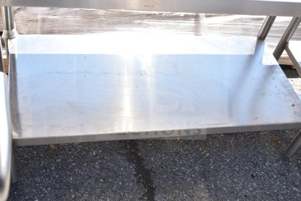 Stainless steel commercial table with under shelf, showing light wear, sturdy design for kitchen or restaurant use.