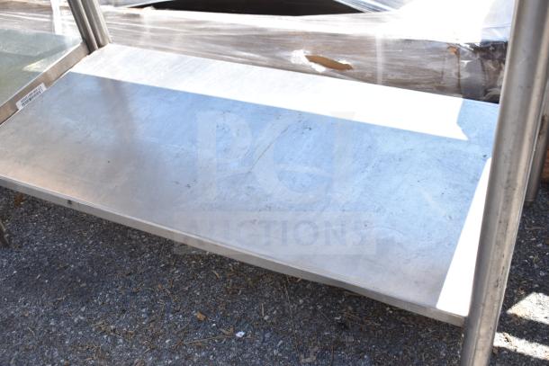 Commercial stainless steel table with backsplash and undershelf, in used condition. Sturdy design for kitchen or industrial use.