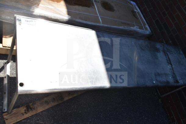 Stainless steel commercial over shelf, used condition, some surface wear, mounted on a pallet for transport.