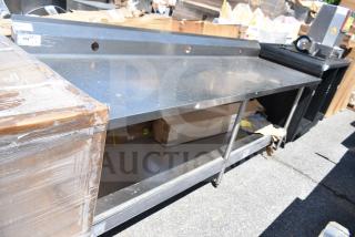Winholt commercial table with backsplash and under shelf, stainless steel, used condition, auction tag visible.