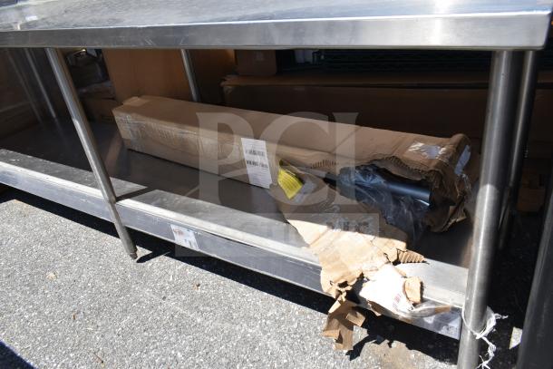 Winholt commercial table with backsplash and under shelf, stainless steel, sturdy legs, good condition, visible cardboard packaging.