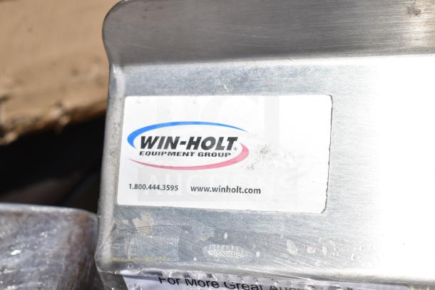 Winholt commercial table with back splash and under shelf. Features a visible label with contact info, in good condition.