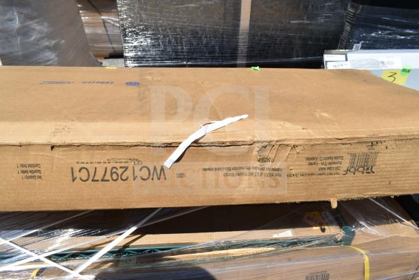 Eight boxes labeled WCL297TCL, containing new scratch and dent items like pan racks and work tables, in cardboard packaging.