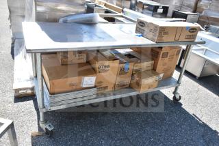 Commercial metal table with wheels, holding boxes of Libbey glasses and baking pans. Good condition, suitable for catering.