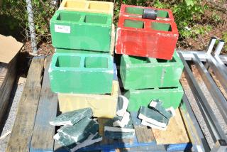 Colorful cinderblocks stacked on pallets; includes green, yellow, and red blocks. Some blocks are broken. Quantity tag visible.