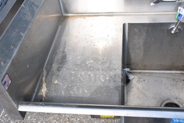 Commercial 3 Bay Sink with dual drain boards, stainless steel, visible wear, American flag sticker, utility tags present.