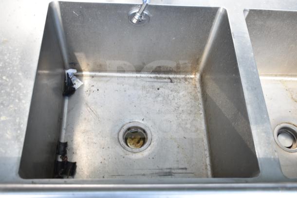 Commercial 3 bay sink with dual drain boards, stainless steel, visible wear and residue, industrial faucet attached.