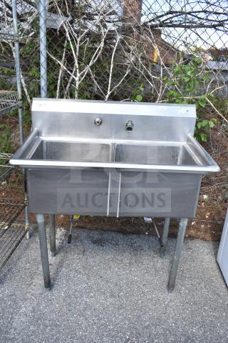 Commercial 2 Bay Sink, stainless steel, durable construction, dual basins, metal legs, some visible wear, for industrial use.