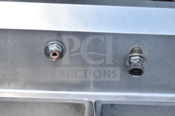 Stainless steel commercial 2 bay sink in good condition, featuring sturdy construction and visible plumbing fittings.