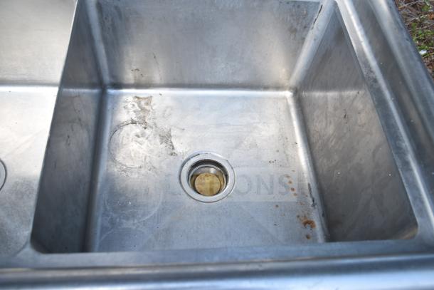 Stainless steel commercial 2 bay sink with visible wear and stains, featuring two deep basins and central drains.