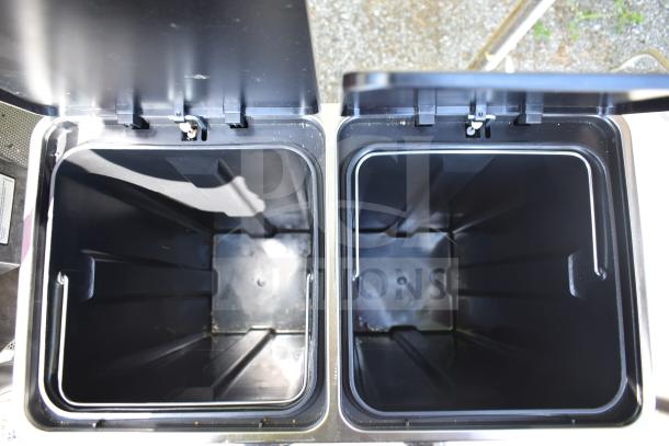 Dual compartment trash can with open lids, black interior, and silver outer frame, in good condition.