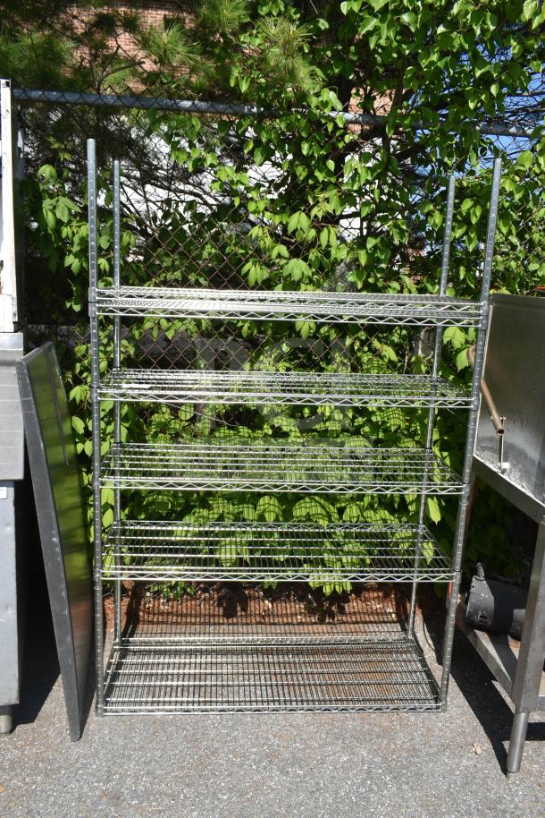 Chrome finish 5-tier wire shelving unit, outdoor setting, sturdy metal construction, dismantling required for buyer.