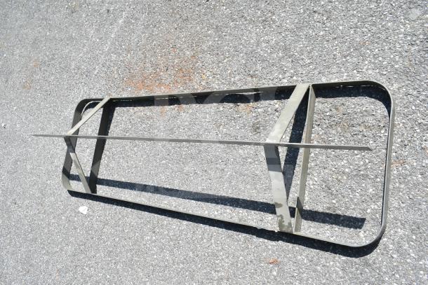 Commercial pot rack made of metal, rectangular frame with crossbars, placed on asphalt surface, used condition.