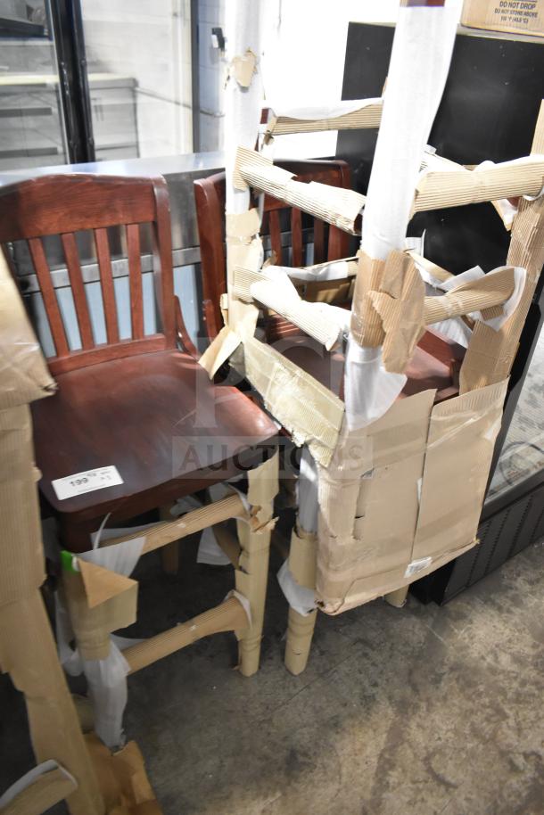 Three brand new wooden bar height chairs with protective wrapping. Visible minor scratches and cardboard padding.